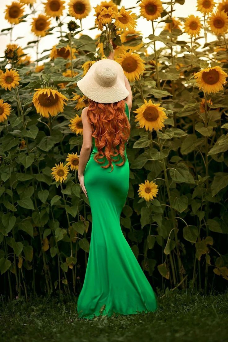 cute redhead in green dress in field of sunflowers
