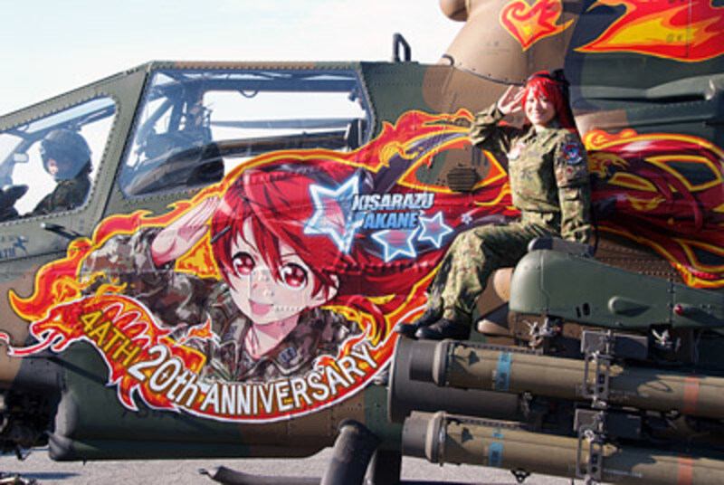 Helicopter gunship with anime side art, and a young woman who looks like the anime character is sitting on the main weapons.
