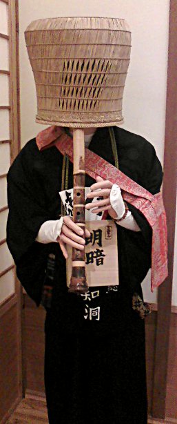 monk playing a shakuhachi with a basket on his head