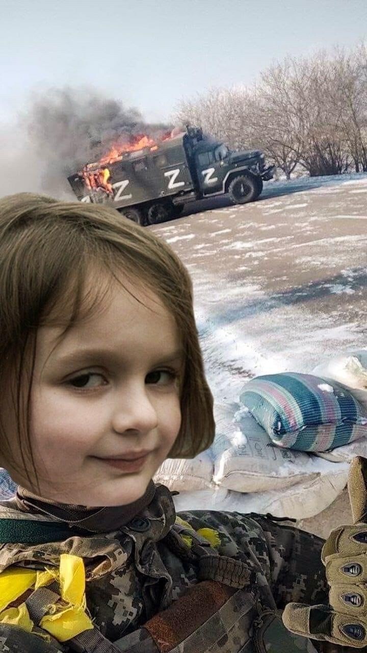 Burning Russian truck and Ukraine soldier giving thumbs-up.  Ukraine soldier's head has been swapped with an internet-famous young girl's.