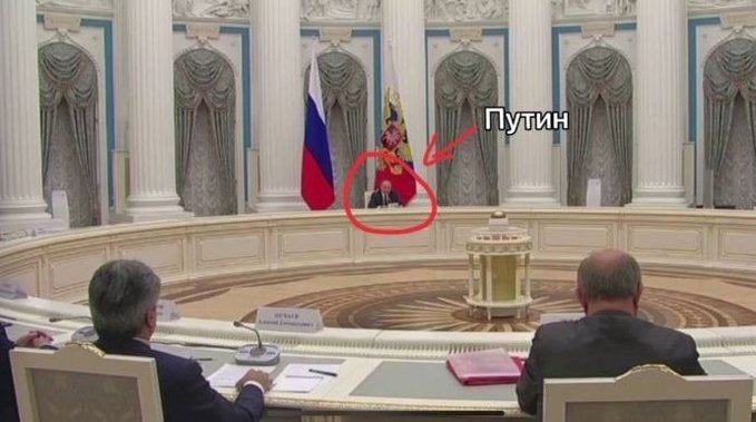 Putin sitting at a table very, very far away from people he is meeting with