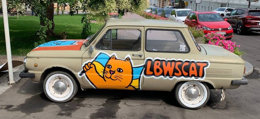 an older car with a painting of LBWScat holding a Ukraine flag