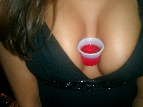 brunette carrying a drink between her breasts