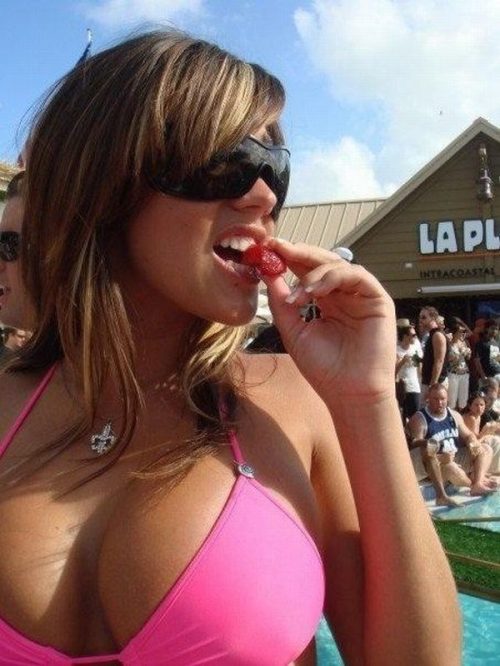 brunette in pink bikini eating a strawberry